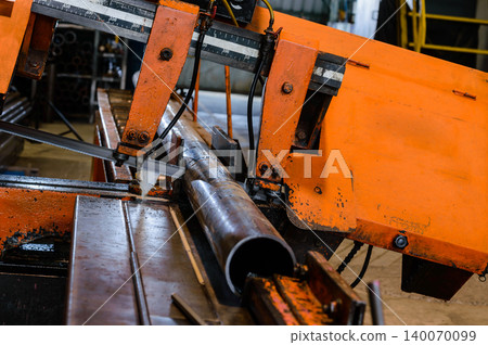 orange colored industrial cutting machine in working processed doing cutting a steel pipe in factory 140070099