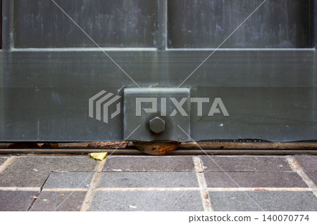 Detail of rusty iron wheel of a dark green sliding gate on rail. Detail of rusty iron wheel of a dark green sliding gate on rail. 140070774