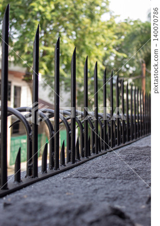 Black iron security fence with sharp spearheads on a wall. Black iron security fence with sharp spearheads on a wall. 140070786