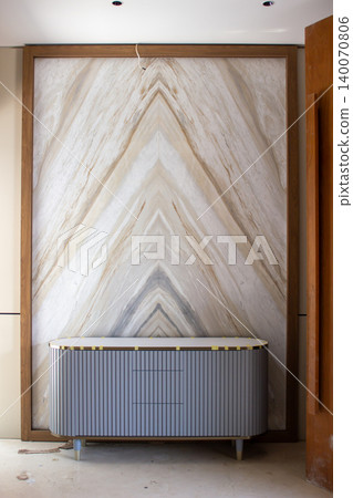 Bookmatch marble wall panel with a modular grey drawer cabinet. 140070806