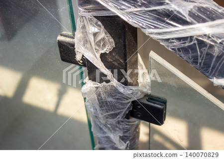 Tempered glass balcony railing with black post wrapped in plastic. Tempered glass balcony railing with black post wrapped in plastic. 140070829