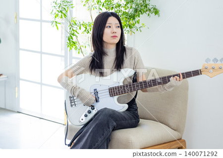 A woman who enjoys playing musical instruments, specifically the bass guitar. A woman who enjoys playing musical instruments, specifically the bass guitar. 140071292