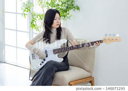 一位喜歡演奏樂器,特別是貝斯吉他的女性。 一位喜歡演奏樂器,特別是貝斯吉他的女性。 140071293