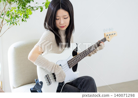 A woman who enjoys playing musical instruments, specifically the bass guitar. A woman who enjoys playing musical instruments, specifically the bass guitar. 140071298