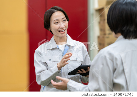 Middle-aged women having a meeting in a warehouse Middle-aged women having a meeting in a warehouse 140071745