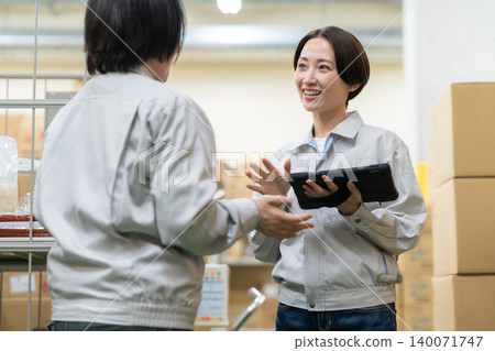 Middle-aged women having a meeting in a warehouse Middle-aged women having a meeting in a warehouse 140071747
