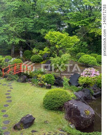 A charming Japanese garden with beautiful fresh greenery and a vermilion bridge. A charming Japanese garden with beautiful fresh greenery and a vermilion bridge. 140071788