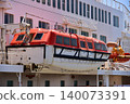Under a blue sky, the lifeboats and hull of a luxury cruise ship docked in Yokohama Port. 140073391