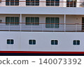 Under the blue sky, the white hull of a luxury cruise ship docked in Yokohama Port is lined with windows. 140073392
