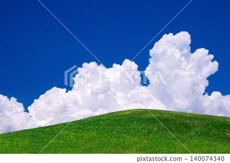 A landscape of green hills with a blue sky and white clouds. 140074340