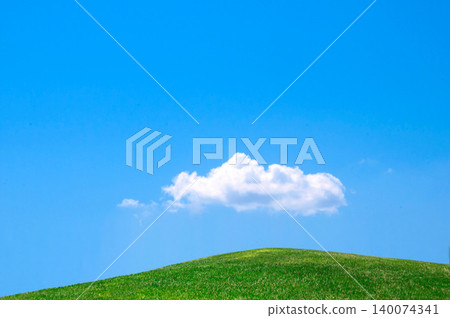 A landscape of green hills with a blue sky and white clouds. 140074341