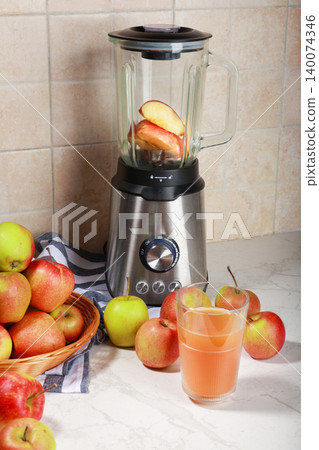 Stainless steel blender with apple slices inside, surrounded by fresh red and green apples and a glass of juice on a marble kitchen counter. Perfect for healthy lifestyle themes. High quality photo Stainless steel blender with apple slices inside, surrounded by fresh red and green apples and a glass of juice on a marble kitchen counter. Perfect for healthy lifestyle themes. High quality photo 140074346
