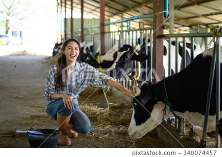 Funny woman farm worker touching cow as sign of concern for animal health care. Concept agriculture Dairy farm farming industry Funny woman farm worker touching cow as sign of concern for animal health care. Concept agriculture Dairy farm farming industry 140074457
