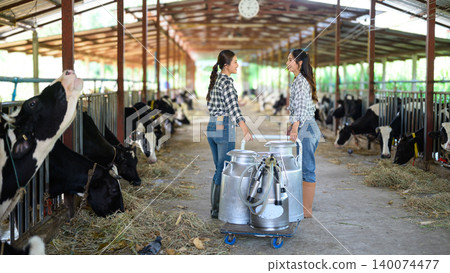 Dairy farm workers using milking equipment and managing milk production in barn Dairy farm workers using milking equipment and managing milk production in barn 140074477