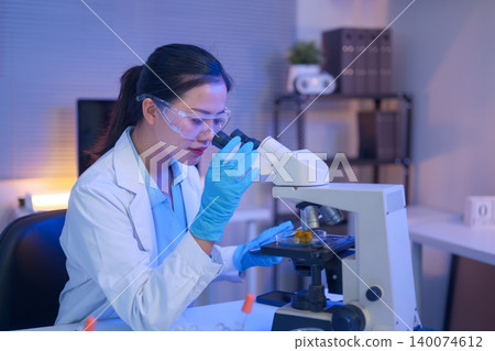 Female scientist using a microscope to analyze samples 140074612