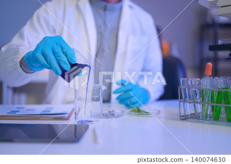 Scientist pours a purple liquid into a beaker during laboratory testing Scientist pours a purple liquid into a beaker during laboratory testing 140074630