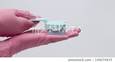 Dentist hands in pink gloves holding a dental impression tray with purple material. Copy space. Dentist hands in pink gloves holding a dental impression tray with purple material. Copy space. 140074835