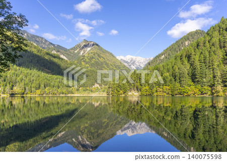 Amazing view of Mirror Lake with crystal clear water among mountains and evergreen woods in Jiuzhaigou nature reserve (Jiuzhai Valley National Park),China. Amazing view of Mirror Lake with crystal clear water among mountains and evergreen woods in Jiuzhaigou nature reserve (Jiuzhai Valley National Park),China. 140075598