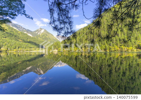Amazing view of Mirror Lake with crystal clear water among mountains and evergreen woods in Jiuzhaigou nature reserve (Jiuzhai Valley National Park),China. Amazing view of Mirror Lake with crystal clear water among mountains and evergreen woods in Jiuzhaigou nature reserve (Jiuzhai Valley National Park),China. 140075599