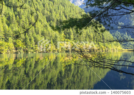 Amazing view of Mirror Lake with crystal clear water among mountains and evergreen woods in Jiuzhaigou nature reserve (Jiuzhai Valley National Park),China. Amazing view of Mirror Lake with crystal clear water among mountains and evergreen woods in Jiuzhaigou nature reserve (Jiuzhai Valley National Park),China. 140075603