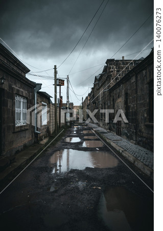 Dark, wet alleyway between old stone buildings under stormy sky Dark, wet alleyway between old stone buildings under stormy sky 140076273