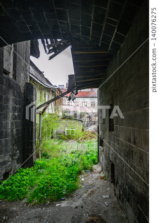Rural stone alley framed by mossy walls and broken eaves Rural stone alley framed by mossy walls and broken eaves 140076275