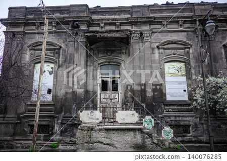 Ruined structure with damaged doors, faded signage, and moss-covered stones 140076285