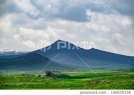 Dramatic mountain silhouette dominates vast grassland Dramatic mountain silhouette dominates vast grassland 140076336