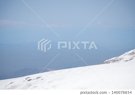 The remaining snow on the high mountains of Asahidake in Hokkaido, the distant mountain range shrouded in spring haze, and a high-key, minimalist snowfield. The remaining snow on the high mountains of Asahidake in Hokkaido, the distant mountain range shrouded in spring haze, and a high-key, minimalist snowfield. 140076654