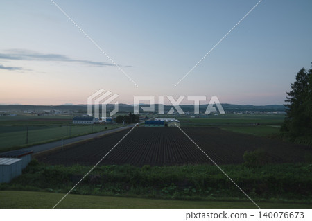 北海道東部的暮色鄉村,廣闊的農田,地平線,初夏的黎明。 北海道東部的暮色鄉村,廣闊的農田,地平線,初夏的黎明。 140076673