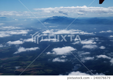 A panoramic view of the sea of clouds, mountain ranges, rice fields, and lakes from an airplane over Hokkaido. 140076679
