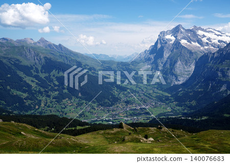 A panoramic view of the Grindelwald Valley in Switzerland, with snow-capped mountains and green plateaus. A panoramic view of the Grindelwald Valley in Switzerland, with snow-capped mountains and green plateaus. 140076683