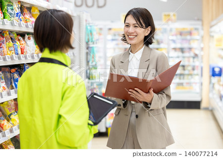 A female employee at a supermarket consults with store staff. A female employee at a supermarket consults with store staff. 140077214