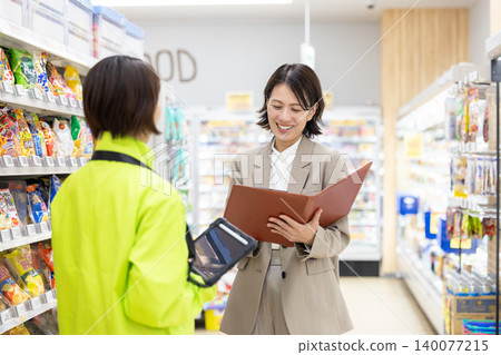 A female employee at a supermarket consults with store staff. 140077215