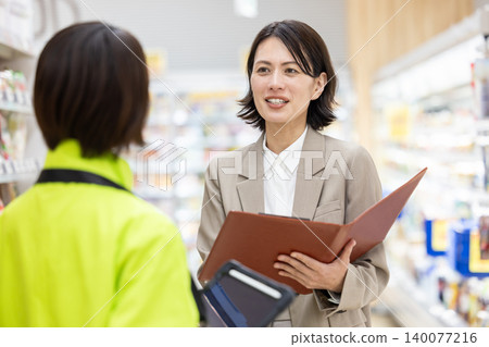 A female employee at a supermarket consults with store staff. A female employee at a supermarket consults with store staff. 140077216
