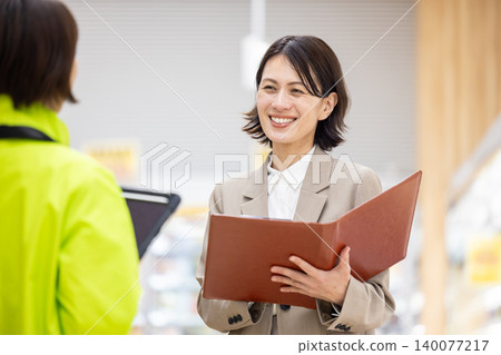 超市女員工正向店員諮詢。 超市女員工正向店員諮詢。 140077217