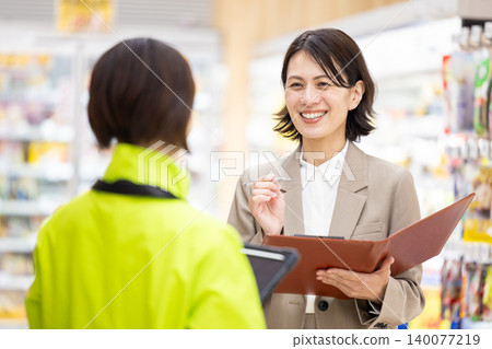 超市女員工正向店員諮詢。 超市女員工正向店員諮詢。 140077219