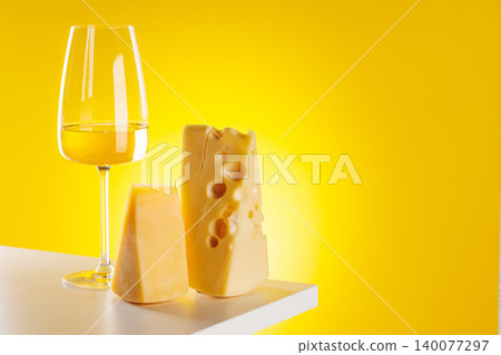 Glass of white wine with cheese on yellow background food pairing concept Glass of white wine with cheese on yellow background food pairing concept 140077297