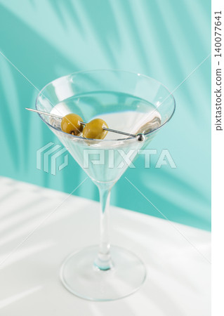Classic martini cocktail with olives in glass on blue background Classic martini cocktail with olives in glass on blue background 140077641