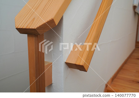 The wall of an indoor staircase with a wooden handrail 140077770