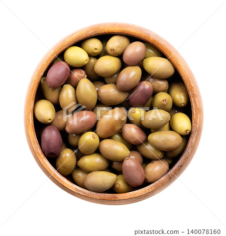 Taggiasca olives with stone, colorful mix of small Italian olives in a wooden bowl. Whole, unripe, cured green olives, and ripe, purple olives, preserved in brine. Isolated close-up, from above. Photo 140078160