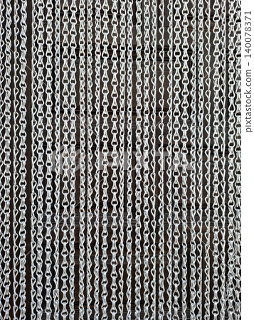 A silver metallic chain link fly screen curtain covers a door. The curtain hangs straight, allowing some light to pass through. This scene takes place indoors during daytime. A silver metallic chain link fly screen curtain covers a door. The curtain hangs straight, allowing some light to pass through. This scene takes place indoors during daytime. 140078371