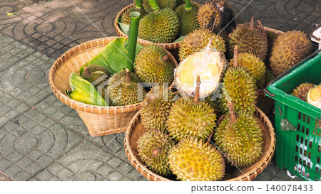 Fresh durian fruits with spiky shell for sale in bamboo baskets on street market Fresh durian fruits with spiky shell for sale in bamboo baskets on street market 140078433
