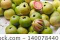 Fresh pink guava fruits with one sliced showing red interior, top view 140078440