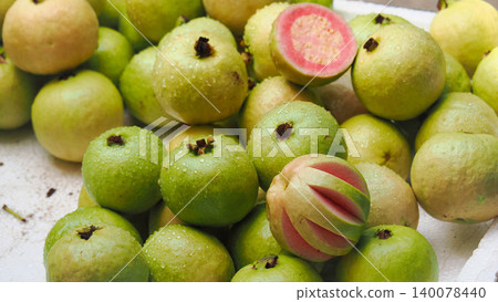Fresh pink guava fruits with one sliced showing red interior, top view Fresh pink guava fruits with one sliced showing red interior, top view 140078440