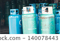Collection of various weathered green and blue liquid petroleum gas (LPG) cylinders in storage 140078443