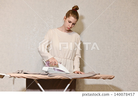 woman irons linen and clothes home, laundry housework textile care. female housewife 140078457