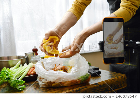Chopping yellow bell pepper over a bag while preparing ingredients in the kitchen Chopping yellow bell pepper over a bag while preparing ingredients in the kitchen 140078547