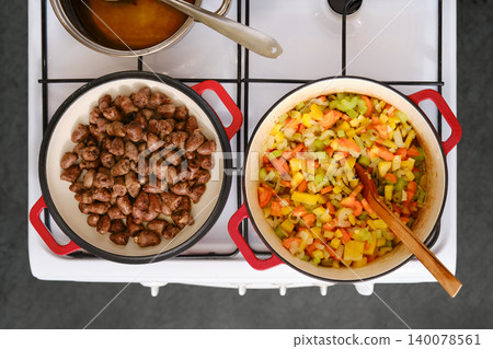 Cooking vegetables and meat on a stove with pot and pan at home in the kitchen Cooking vegetables and meat on a stove with pot and pan at home in the kitchen 140078561