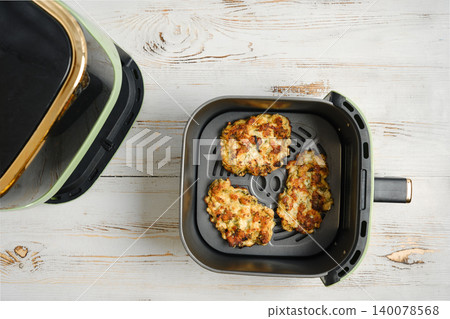 Cooking chicken patties in an air fryer in a kitchen during the day 140078568